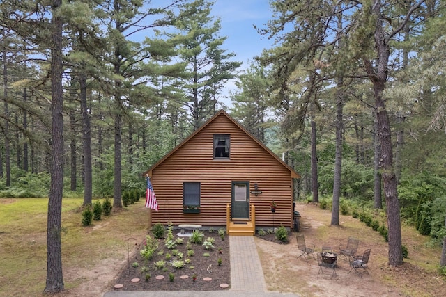 8 Log Cabin Ln Unit 9, Shapleigh, ME 04076 - view of front facade with a fire pit, a wooded view, and log veneer siding