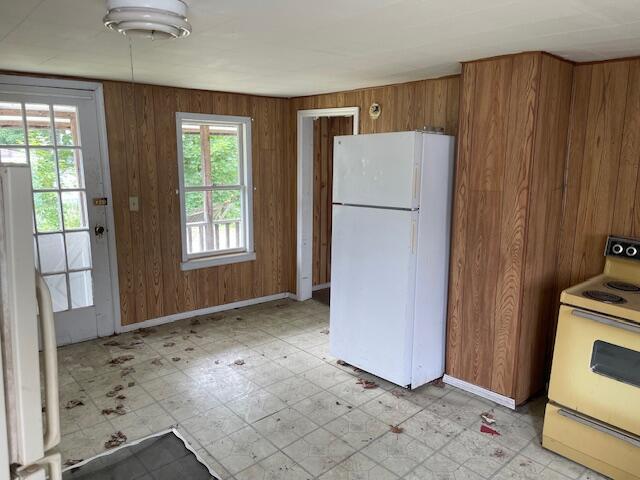 18 Birch St, East Millinocket, ME 04430 - kitchen with white appliances, light flooring, wood walls, and brown cabinets