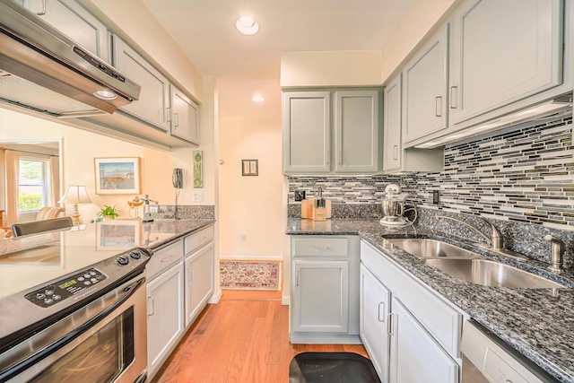 97 Dockside Ln Unit 8, Belfast, ME 04915 - kitchen with stainless steel appliances, range hood, light wood finished floors, recessed lighting, and tasteful backsplash