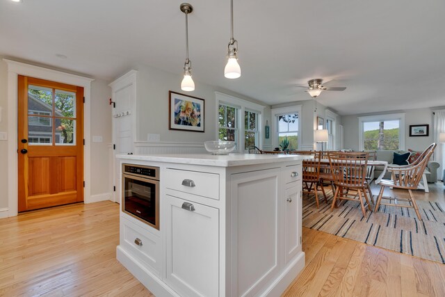 13 Norwood Ln, Kennebunkport, ME 04046 - kitchen with light wood-type flooring, light countertops, hanging light fixtures, white cabinets, and ceiling fan