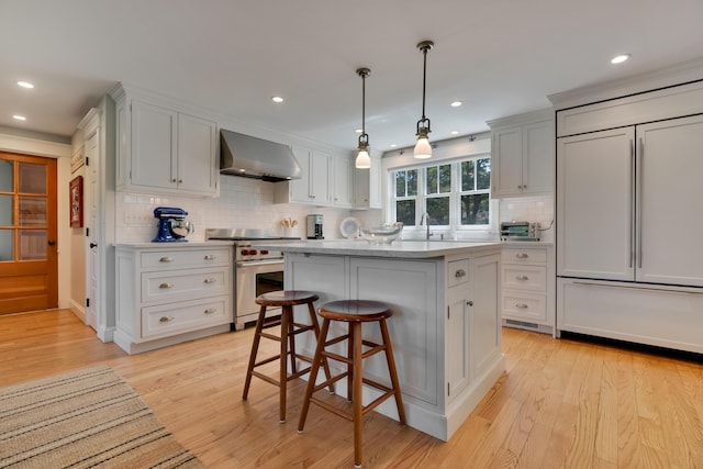 13 Norwood Ln, Kennebunkport, ME 04046 - kitchen with high end appliances, wall chimney range hood, backsplash, light countertops, and recessed lighting