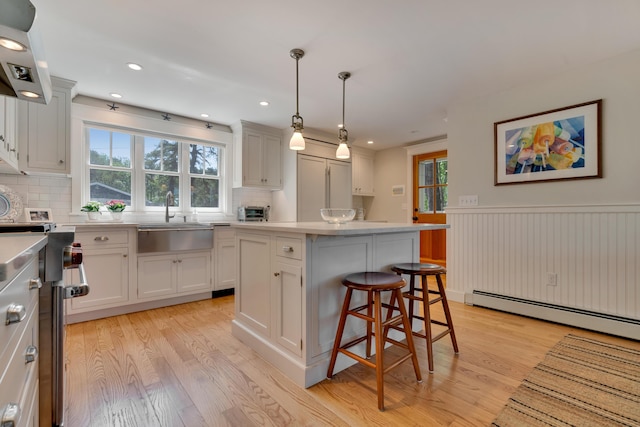 13 Norwood Ln, Kennebunkport, ME 04046 - kitchen featuring light wood-style floors, light countertops, a wainscoted wall, tasteful backsplash, and a breakfast bar area