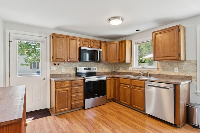 46 Label Ave, Portland, ME 04103 - kitchen with appliances with stainless steel finishes, light wood finished floors, decorative backsplash, and brown cabinetry