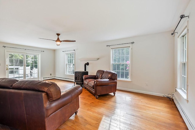 4 Acorn Ln, Lewiston, ME 04240 - living area with a baseboard heating unit, a wood stove, light wood-style floors, and a ceiling fan