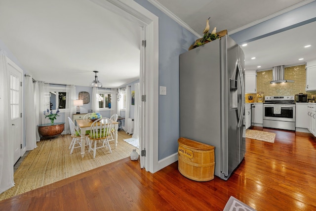 12 Fillmore Ave, South Portland, ME 04106 - kitchen featuring stainless steel appliances, wall chimney exhaust hood, wood finished floors, backsplash, and white cabinetry