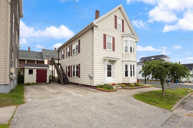 37 Cook St, Auburn, ME 04210 - view of front facade featuring a chimney, a storage unit, and driveway