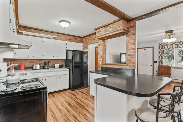 8 Grovemount Ln, Lewiston, ME 04240 - kitchen with black appliances, light wood-style flooring, dark countertops, a kitchen bar, and brick wall