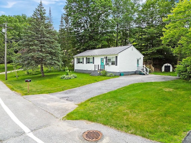 154 Rideout Ave, Lewiston, ME 04240 - view of front of home with a metal roof, a storage unit, asphalt driveway, and a front lawn