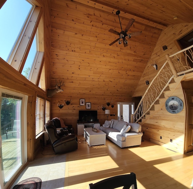 67 Upper Narrows Rd, Long Pond Twp, ME 04945 - living area with wooden walls, high vaulted ceiling, plenty of natural light, a wooden ceiling with exposed beams, and stairs