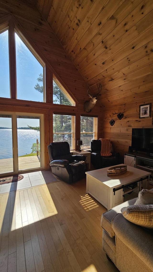 67 Upper Narrows Rd, Long Pond Twp, ME 04945 - living area with a water view, wooden walls, high vaulted ceiling, hardwood / wood-style floors, and wood ceiling