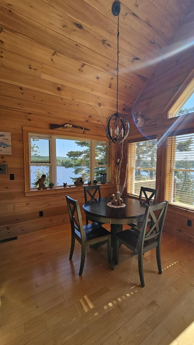 67 Upper Narrows Rd, Long Pond Twp, ME 04945 - dining area featuring wood walls, a chandelier, healthy amount of natural light, light wood finished floors, and lofted ceiling