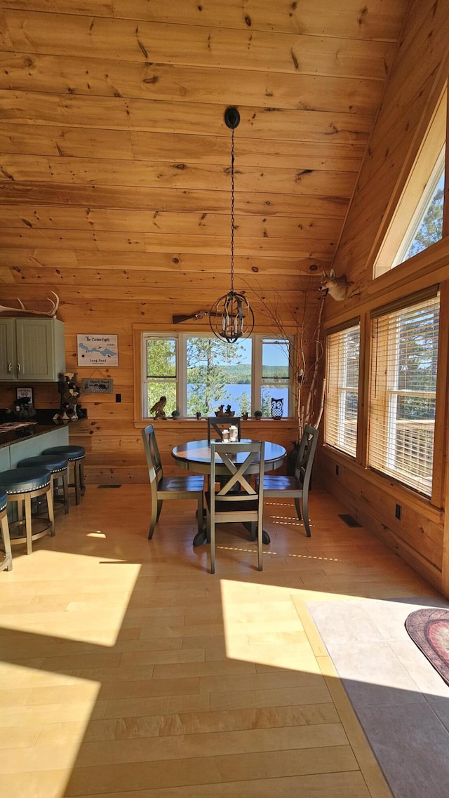 67 Upper Narrows Rd, Long Pond Twp, ME 04945 - dining room featuring healthy amount of natural light, hardwood / wood-style floors, a chandelier, wood walls, and lofted ceiling