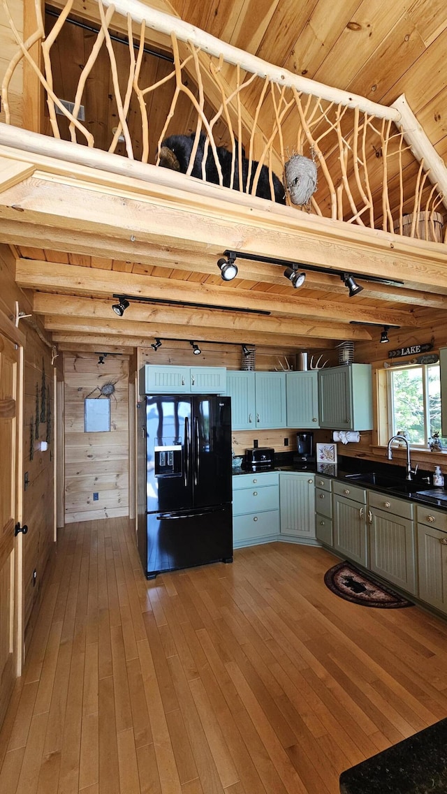 67 Upper Narrows Rd, Long Pond Twp, ME 04945 - kitchen featuring black refrigerator with ice dispenser, dark countertops, light wood-type flooring, and wood walls