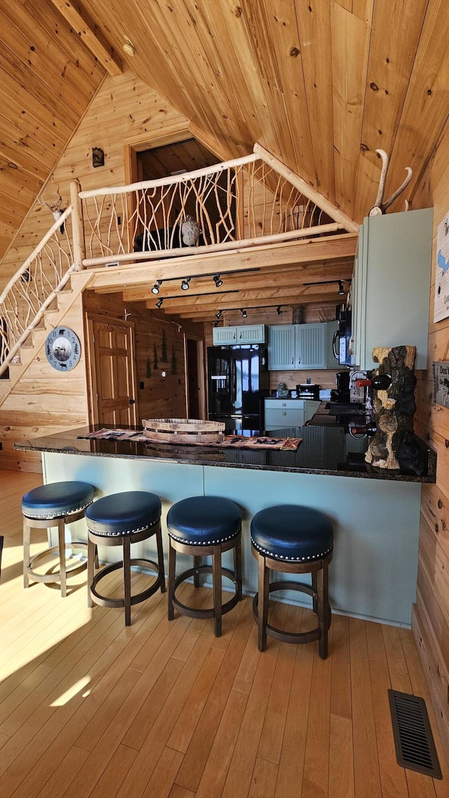 67 Upper Narrows Rd, Long Pond Twp, ME 04945 - kitchen with wood ceiling, wood walls, vaulted ceiling, black appliances, and hardwood / wood-style floors