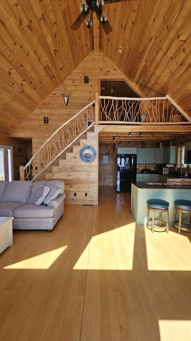 67 Upper Narrows Rd, Long Pond Twp, ME 04945 - living area with lofted ceiling, wooden ceiling, wood walls, a ceiling fan, and hardwood / wood-style floors