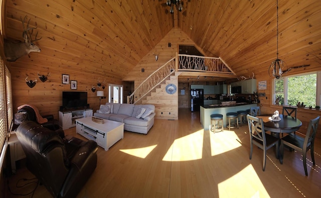 67 Upper Narrows Rd, Long Pond Twp, ME 04945 - living area featuring wooden walls, wooden ceiling, light wood-style flooring, stairway, and high vaulted ceiling