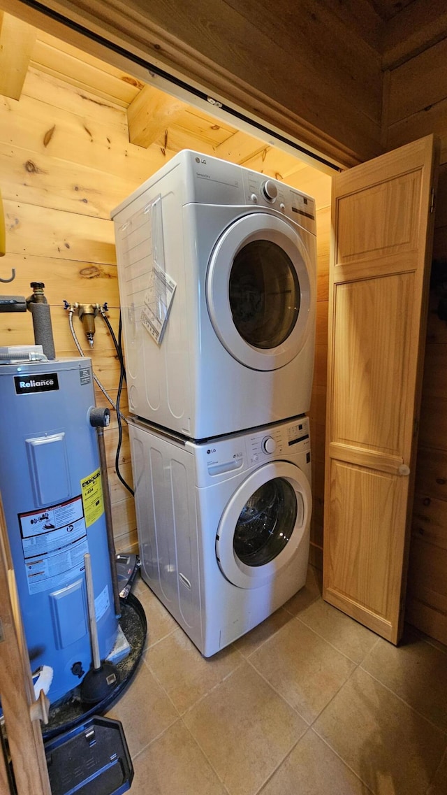 67 Upper Narrows Rd, Long Pond Twp, ME 04945 - laundry room with stacked washer and clothes dryer, water heater, light tile patterned flooring, and wooden walls