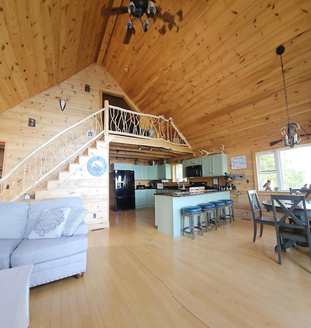 67 Upper Narrows Rd, Long Pond Twp, ME 04945 - living area featuring wood ceiling, wooden walls, high vaulted ceiling, light wood finished floors, and stairway