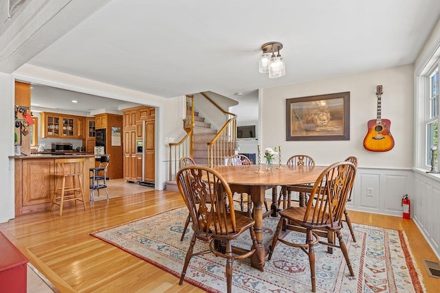 555 Pool St, Biddeford, ME 04005 - dining room featuring light wood finished floors, stairway, and wainscoting