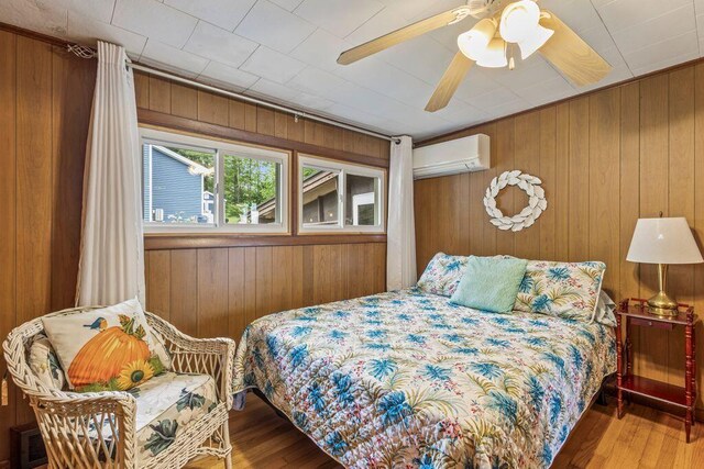 1522 Richville Rd, Standish, ME 04084 - bedroom featuring a wall mounted AC, wood finished floors, wood walls, and a ceiling fan