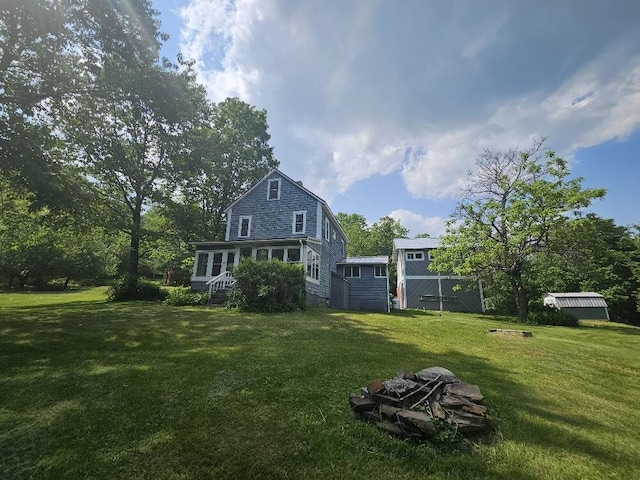 28 Varnum Pond Rd, Temple, ME 04984 - rear view of house featuring an outdoor fire pit, a yard, and a storage shed