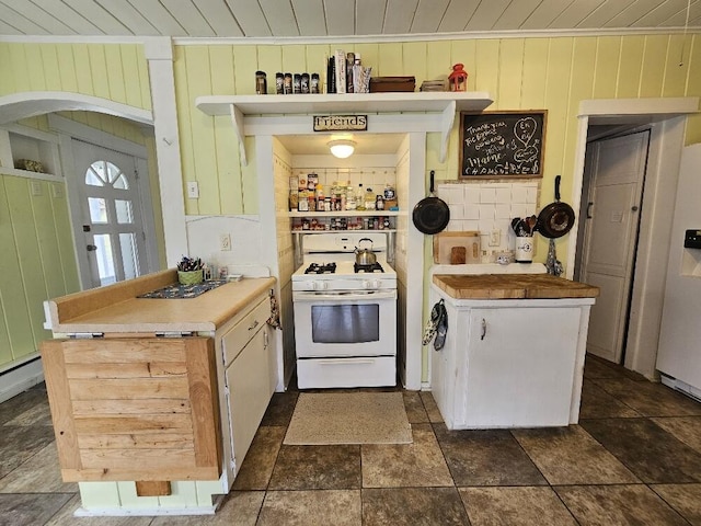 28 Varnum Pond Rd, Temple, ME 04984 - kitchen featuring gas range gas stove, arched walkways, wood ceiling, dark stone finish flooring, and wooden walls