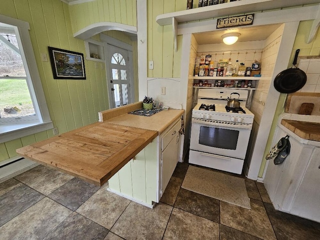 28 Varnum Pond Rd, Temple, ME 04984 - kitchen featuring white range with gas stovetop, wood walls, arched walkways, healthy amount of natural light, and dark stone finish floors