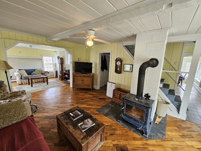 28 Varnum Pond Rd, Temple, ME 04984 - living room featuring hardwood / wood-style floors, a wood stove, beamed ceiling, a ceiling fan, and stairway