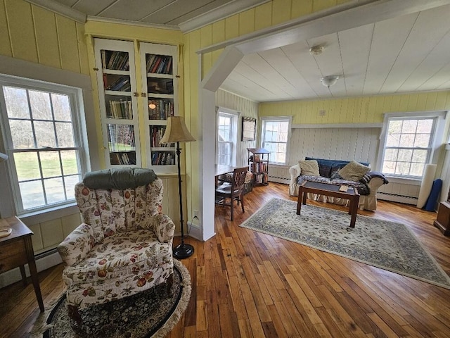 28 Varnum Pond Rd, Temple, ME 04984 - living room with a baseboard heating unit, wooden walls, hardwood / wood-style flooring, ornamental molding, and arched walkways