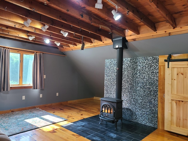 163 Ayer Ridge Rd, Freedom, ME 04941 - unfurnished living room with a wood stove, hardwood / wood-style floors, track lighting, a barn door, and a wood ceiling with exposed beams