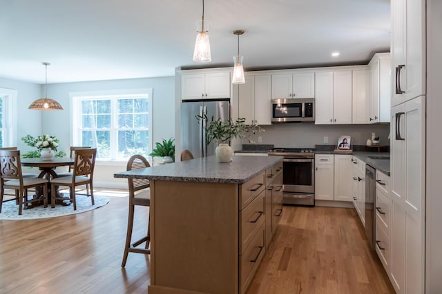 59 Sagamore Dr Lot 28, Phippsburg, ME 04562 - kitchen featuring appliances with stainless steel finishes, light wood-type flooring, a center island, a breakfast bar, and white cabinetry