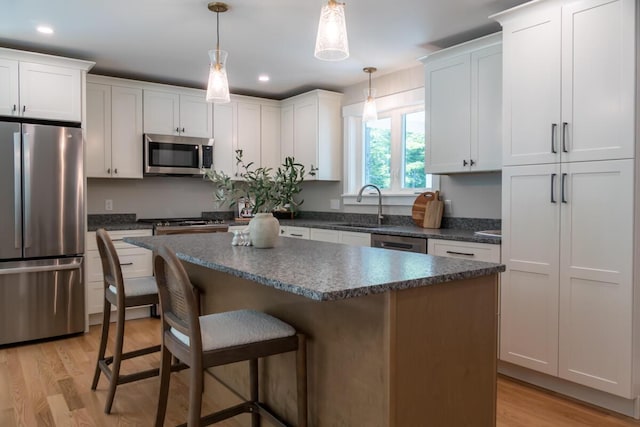 59 Sagamore Dr Lot 28, Phippsburg, ME 04562 - kitchen with stainless steel appliances, dark countertops, light wood-style flooring, a breakfast bar, and a center island