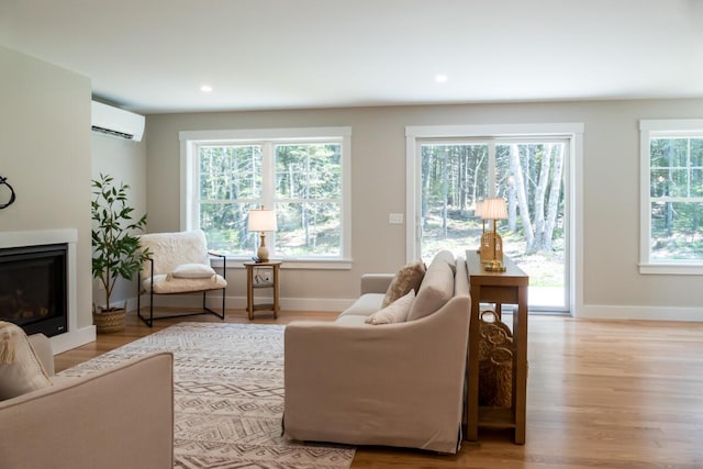 59 Sagamore Dr Lot 28, Phippsburg, ME 04562 - living area with a wall mounted air conditioner, wood finished floors, a glass covered fireplace, and recessed lighting