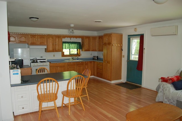 803 Main Rd, Burlington, ME 04417 - kitchen featuring white gas range oven, a wall unit AC, light wood-style floors, brown cabinets, and healthy amount of natural light