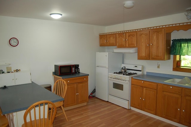 803 Main Rd, Burlington, ME 04417 - kitchen with white appliances, brown cabinetry, light wood-style flooring, dark countertops, and range hood