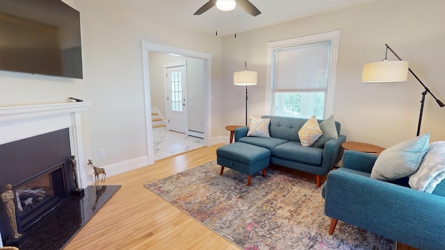 295 French St, Bangor, ME 04401 - living area featuring a baseboard heating unit, stairs, a fireplace, wood finished floors, and a ceiling fan