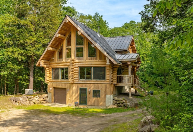 320 Commons Dr, Bridgton, ME 04009 - view of front of property featuring a standing seam roof, driveway, log siding, a garage, and a metal roof