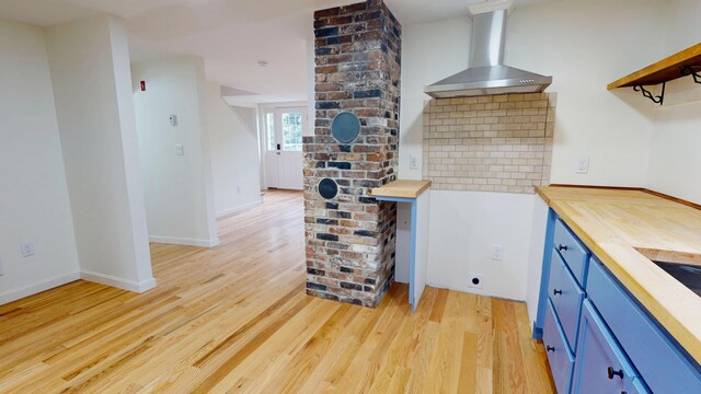 14 Pond St, Orono, ME 04473 - kitchen featuring wall chimney exhaust hood, butcher block countertops, blue cabinets, and light wood-style floors