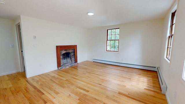 14 Pond St, Orono, ME 04473 - unfurnished living room with a baseboard radiator, a fireplace with raised hearth, wood finished floors, and recessed lighting