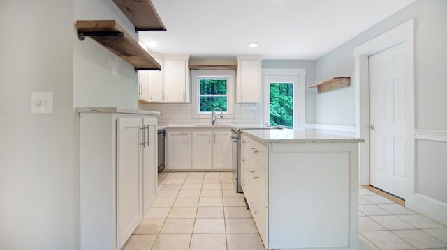 326 Meetinghouse Rd, Wells, ME 04090 - kitchen with tasteful backsplash, a kitchen island, light tile patterned floors, white cabinetry, and light stone countertops