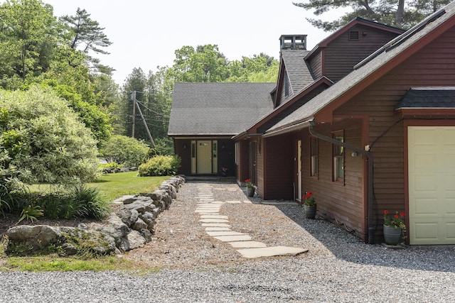 11 Everett Dow Dr, Woolwich, ME 04579 - view of front of house featuring a chimney, a shingled roof, and a garage