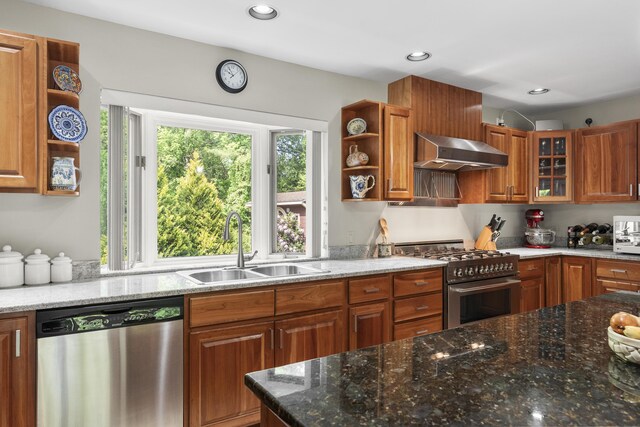 11 Everett Dow Dr, Woolwich, ME 04579 - kitchen with stainless steel appliances, wall chimney range hood, open shelves, brown cabinetry, and dark stone countertops
