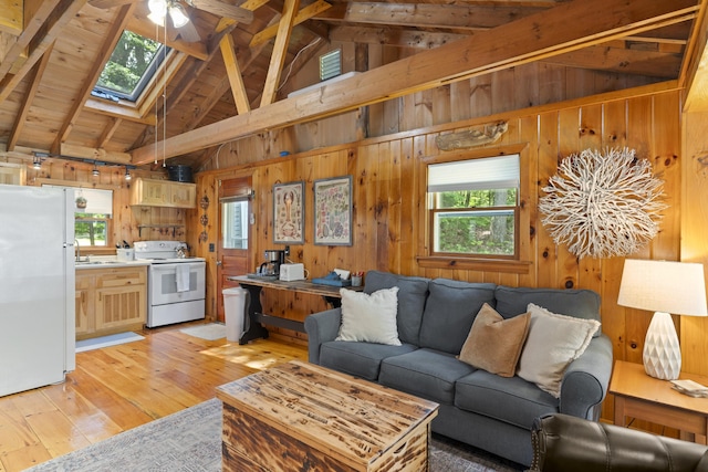 8 N Lakeview Dr, Litchfield, ME 04350 - living room with a skylight, wood walls, light wood-type flooring, a ceiling fan, and high vaulted ceiling