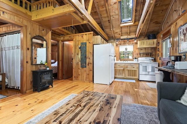 8 N Lakeview Dr, Litchfield, ME 04350 - kitchen with white appliances, wooden walls, a skylight, light wood-type flooring, and a wood stove