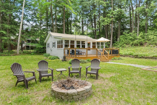 8 N Lakeview Dr, Litchfield, ME 04350 - back of house with an outdoor fire pit, a deck, a yard, a metal roof, and a sunroom