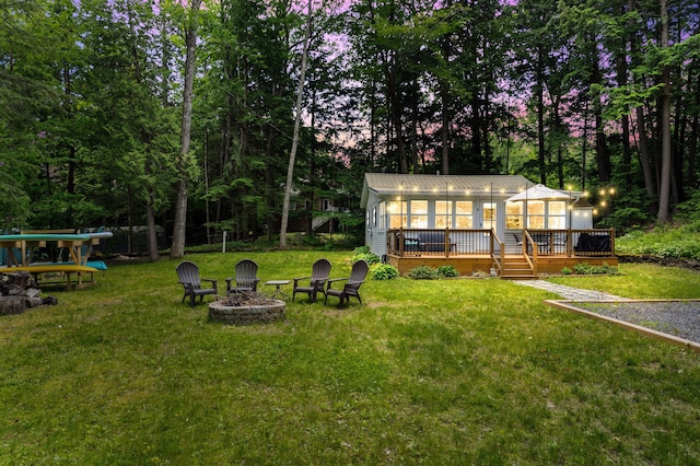 8 N Lakeview Dr, Litchfield, ME 04350 - view of grassy yard with an outdoor fire pit, a sunroom, and a wooden deck