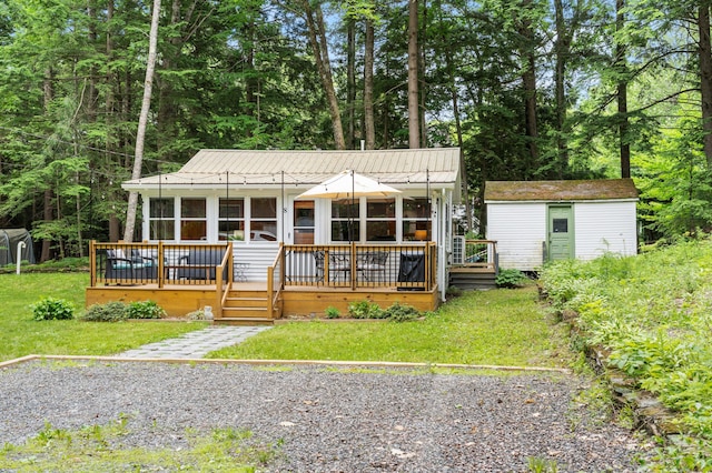8 N Lakeview Dr, Litchfield, ME 04350 - view of front facade featuring a sunroom, a front yard, a shed, and a metal roof