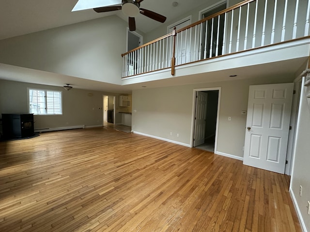 53 Pennacook Cir, Wells, ME 04090 - unfurnished living room featuring high vaulted ceiling, ceiling fan, a wood stove, baseboard heating, and hardwood / wood-style floors