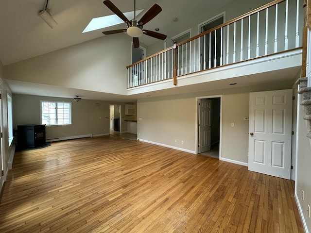 53 Pennacook Cir, Wells, ME 04090 - unfurnished living room with high vaulted ceiling, a wood stove, a baseboard heating unit, ceiling fan, and light wood-type flooring