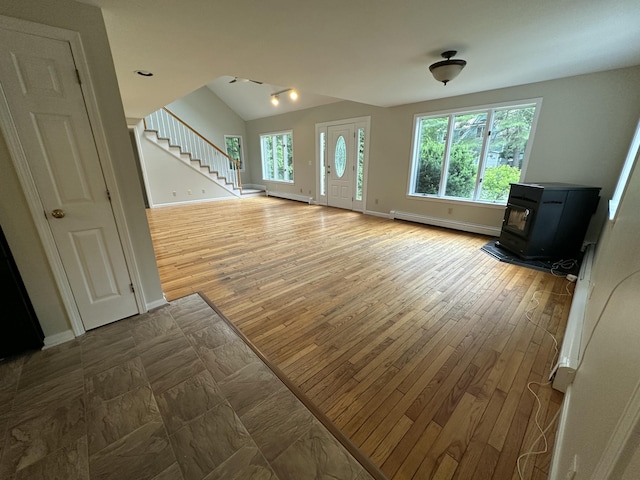 53 Pennacook Cir, Wells, ME 04090 - unfurnished living room featuring baseboard heating, a wood stove, stairway, wood finished floors, and lofted ceiling